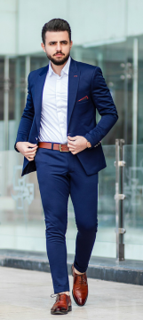 A well-dressed young man with a blue suit, a white shirt and brown shoes