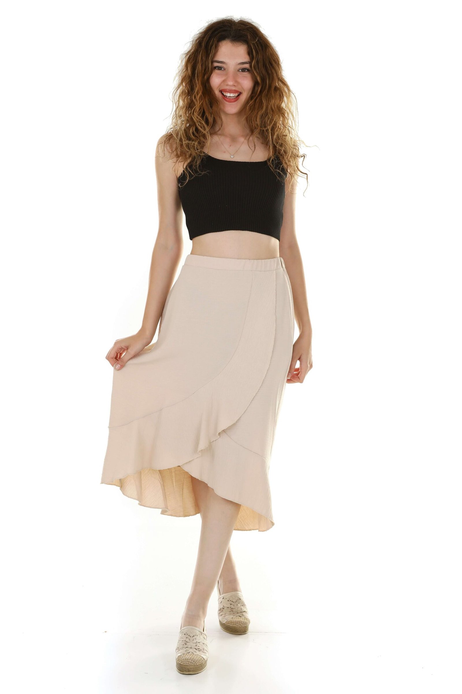 Young blonde women in black mini bra, beige long skirt, and stylish shoes posing confidently.