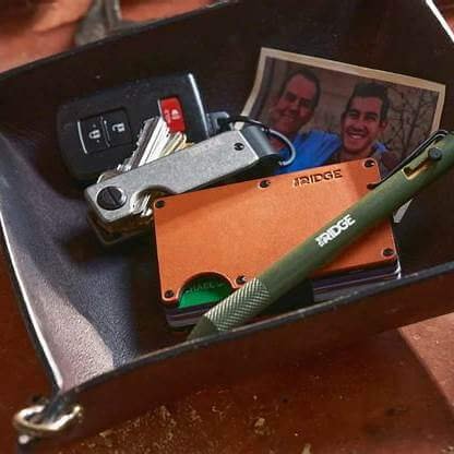 Light brown leather card wallet placed in a small tray, surrounded by keys, a pen, and a photo.